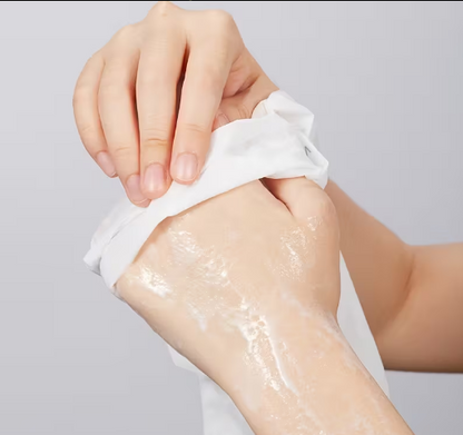 Hand applying a white cream or lotion to another hand on a light gray background