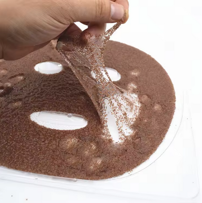 Hand holding a brown sponge over a round brown object with white centers.